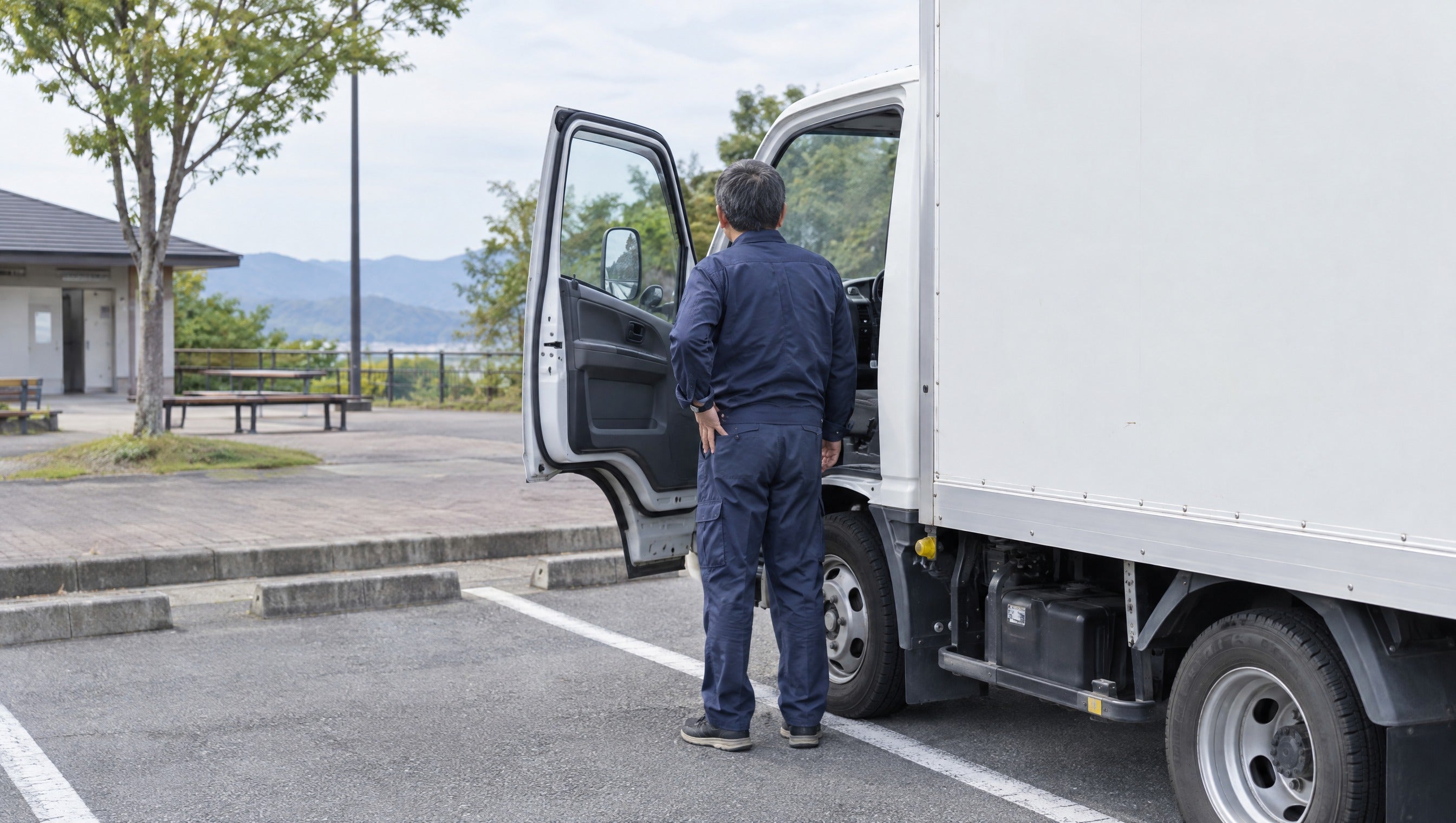 トラックのそばに立つ男性の後ろ姿